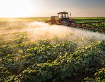 A tractor spraying pesticides into a field.