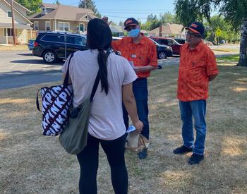 OSU Extension's Jaime Guillen (left) and Rafael Palacios talk to a Newberg resident about a vaccine clinic scheduled for later in the day at the Newberg Public Library.