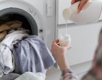 A person adding detergent to a washing machine.
