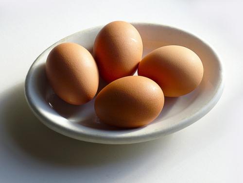 Four brown eggs in a small white bowl