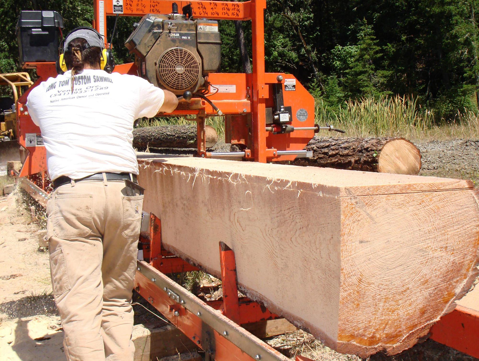 man saws a log using a portable mill on-site