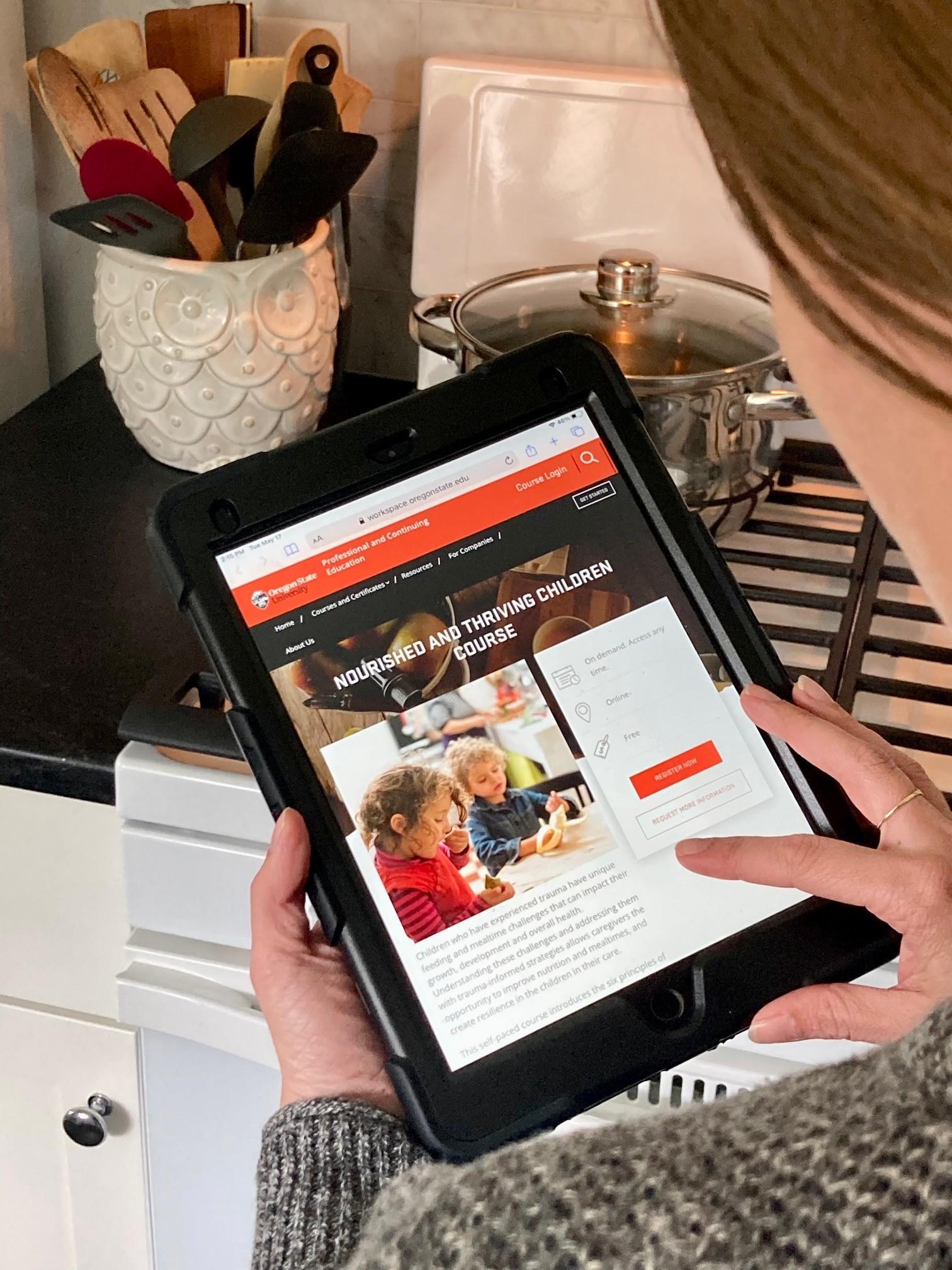 A person is reading about the course on a tablet in their kitchen.