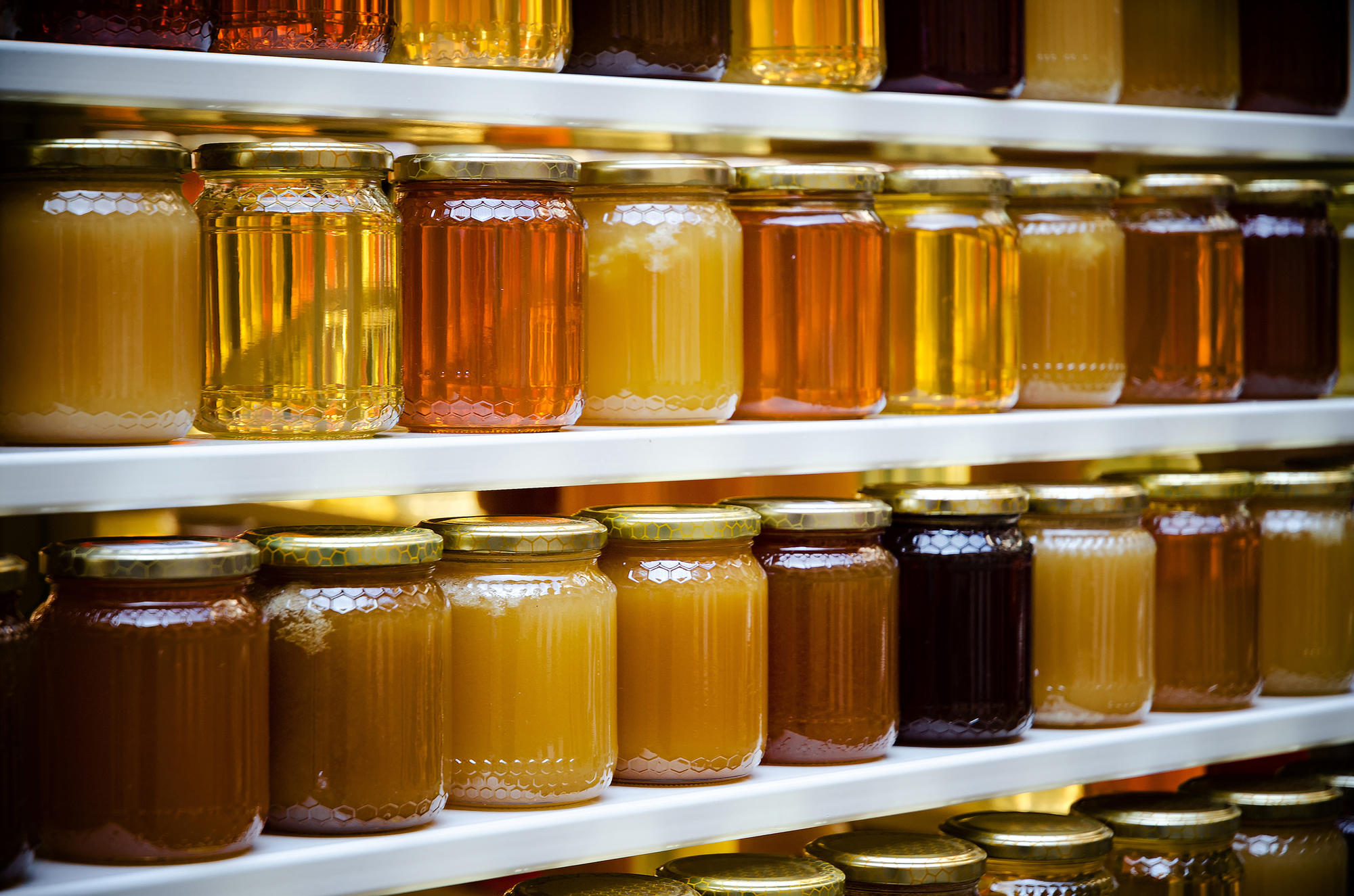 Jars of honey on shelves at a farmers market.