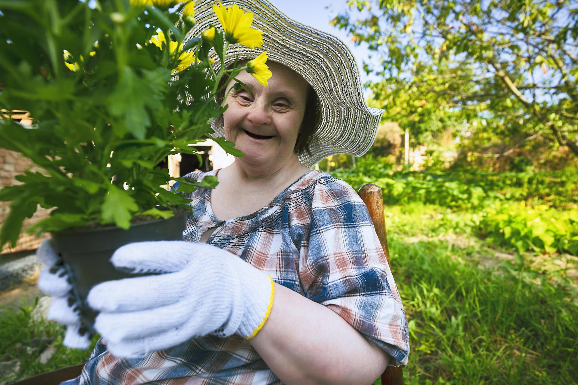 A woman with Down Syndrome plants a flower