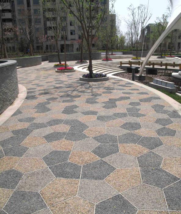 Decorative pervious concrete in a courtyard with alternating dark gray and tan aggregate interlocking tiles.