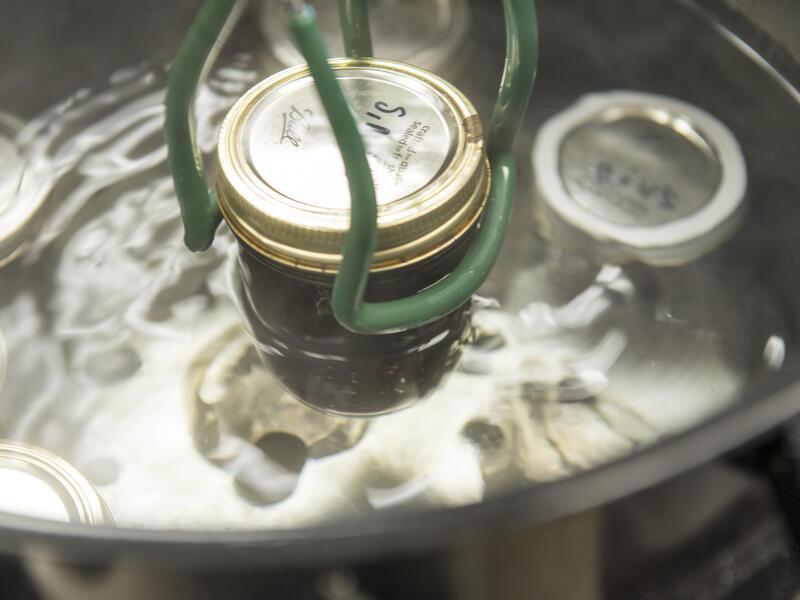 Jam jar being lifted out of a water bath canner