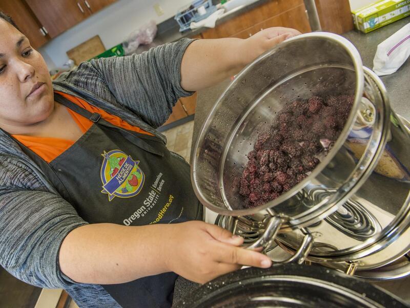 Woman pulling steam juicer off of stove top