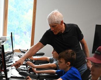 Instructor pointing at screen with YOCLS focusing learning mechanized harvesting on computers.