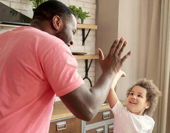 father and young child give/receive high 5