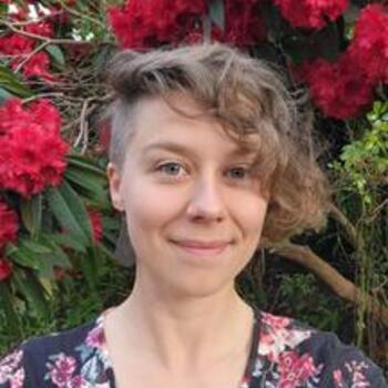Smiling person standing in front of rhododendron in bloom